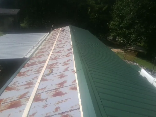 Old rusted panels beside newly installed green metal roofing — Wind Damage Roof Repair by Roofing Brothers in Saint George