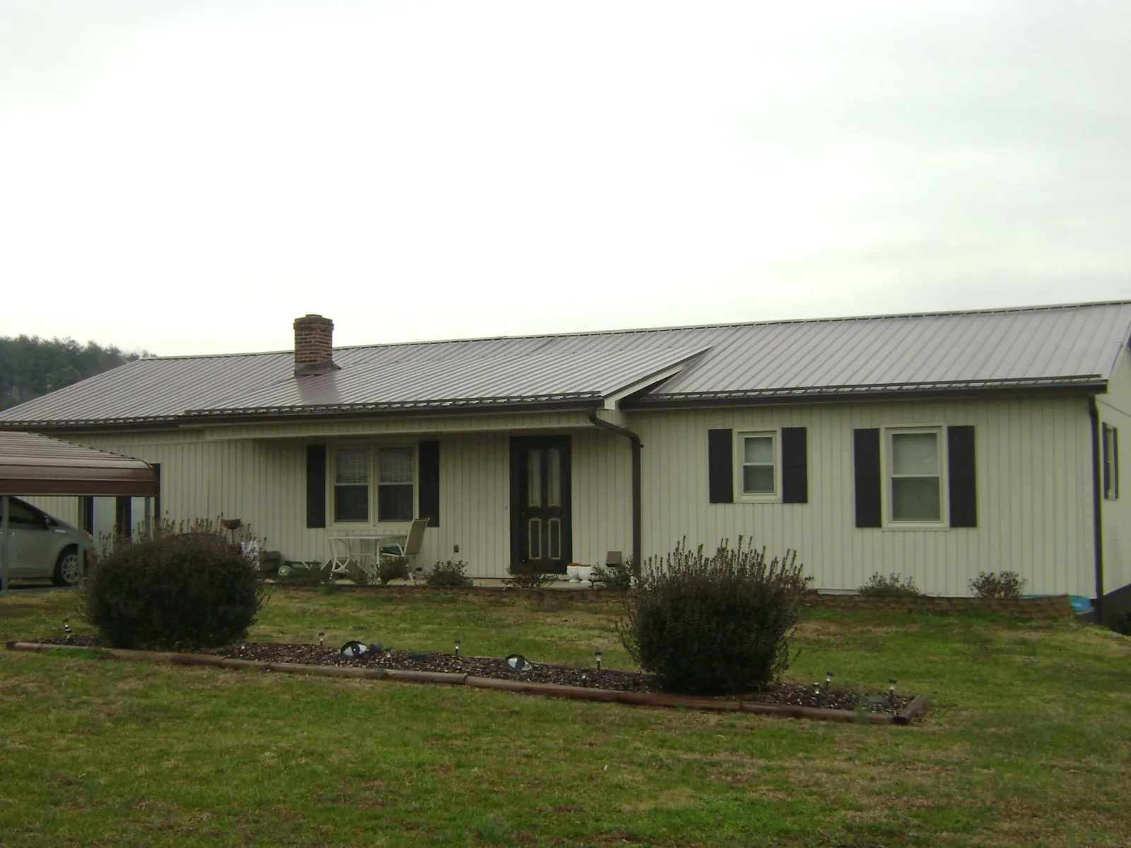 Brown metal roof on a cream sided ranch home with a brick chimney in Saint George