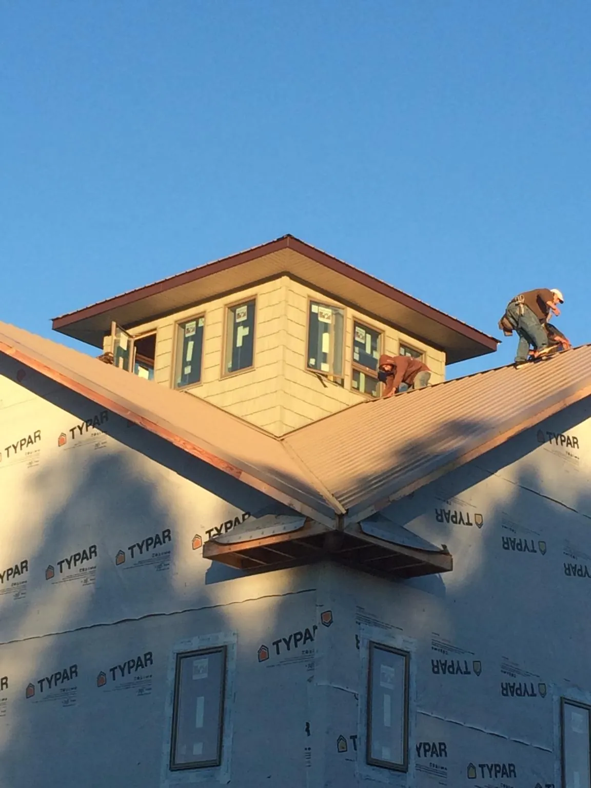 Roofers working around a rooftop cupola on a new metal roof at sunset — Roof Waterproofing in Saint George by Roofing Brothers